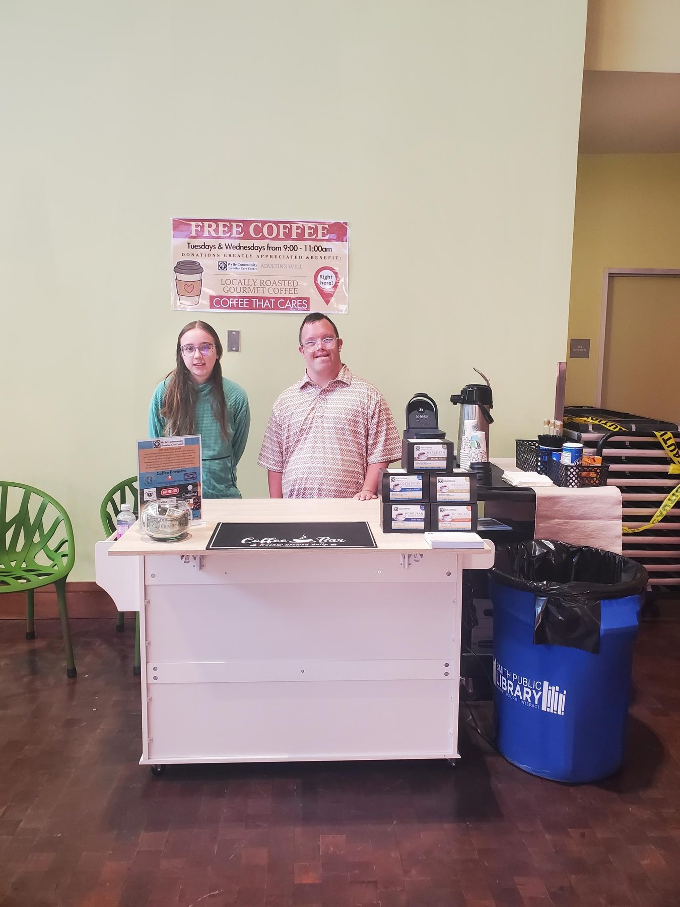 Two Adulting Well students at the Coffee with a Cause cart with banner